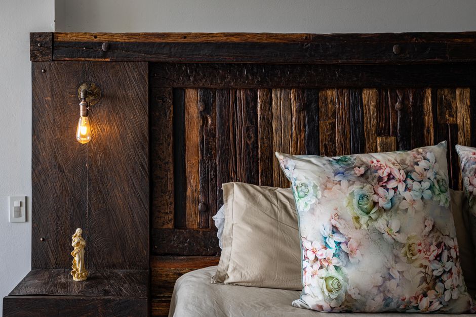 Tête de lit bois massif de style scandinave dans une chambre lumineuse avec murs blancs et linge de lit clair